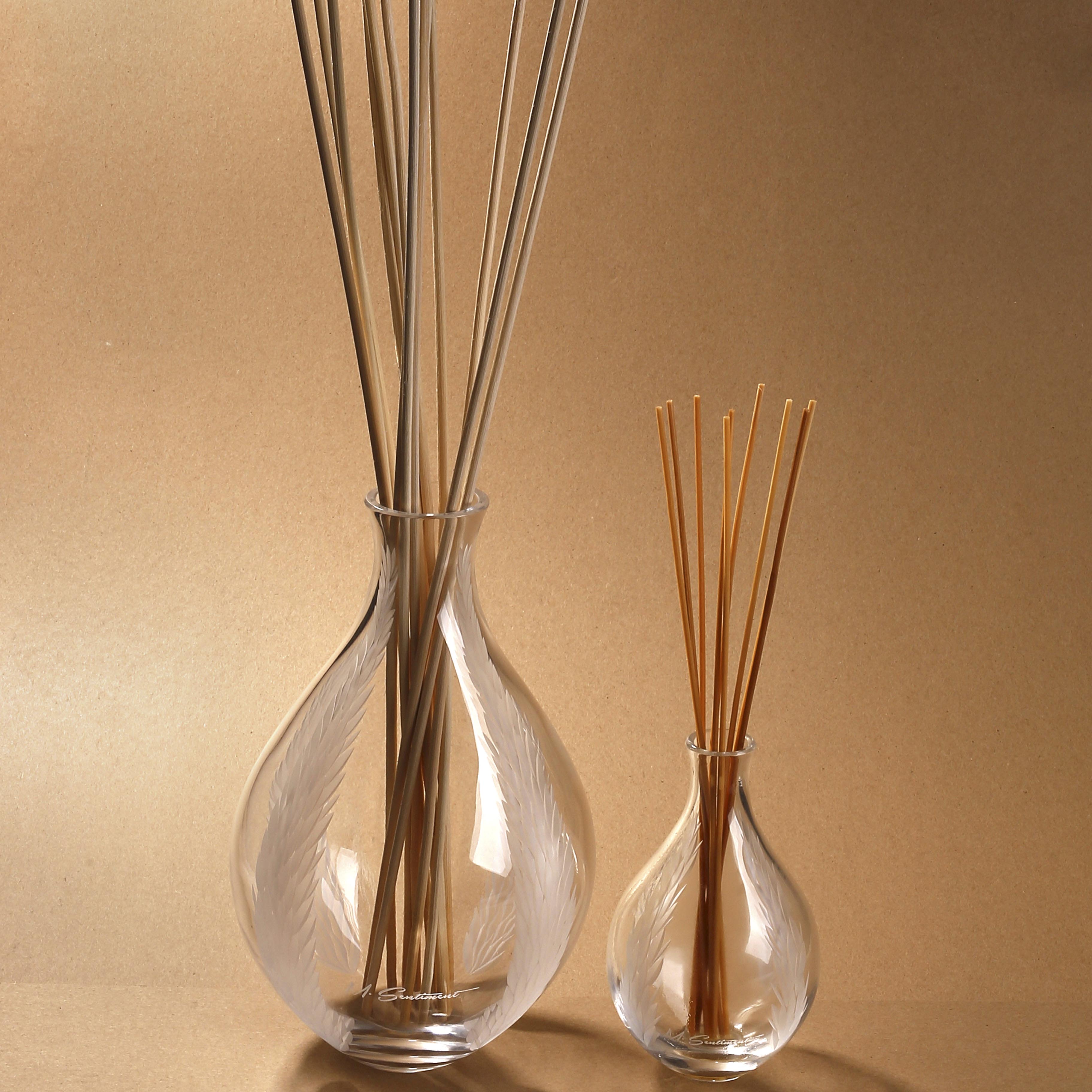 Two glass diffusers with natural rattan sticks; one is larger and has multiple sticks, the other is smaller with just a few sticks.